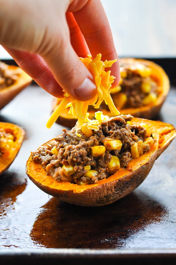 Sprinkling grated cheddar cheese on top of taco stuffed potatoes
