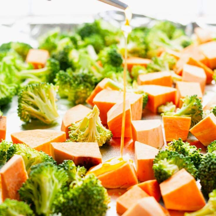 Process shot showing how to make a sheet pan dinner with salmon and sweet potatoes.