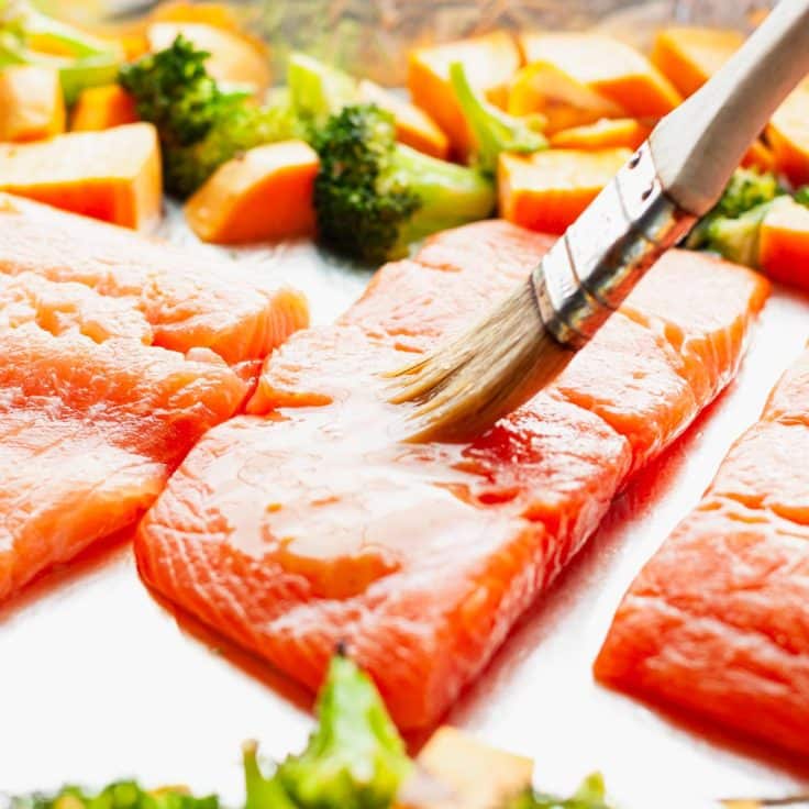 Brushing salmon fillets with a maple mustard glaze.
