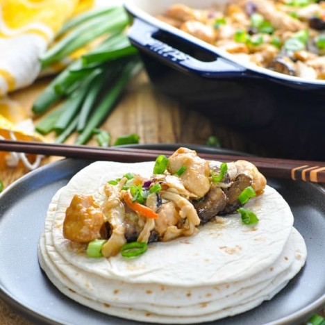 Baked moo shu chicken on top of stack of tortillas with chopsticks