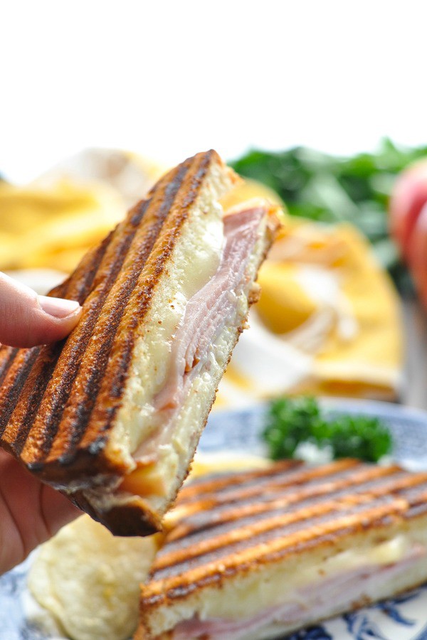 Close up image of a hand holding half of a Ham Brie and Apple Panini Sandwich