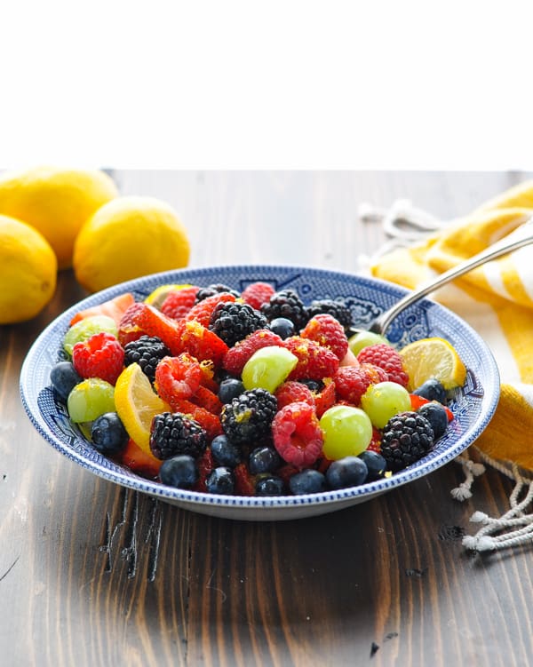 Bowl of fresh fruit salad with lemons in the background