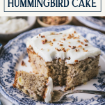 Side shot of a bite out of a piece of hummingbird cake with text title box at top.