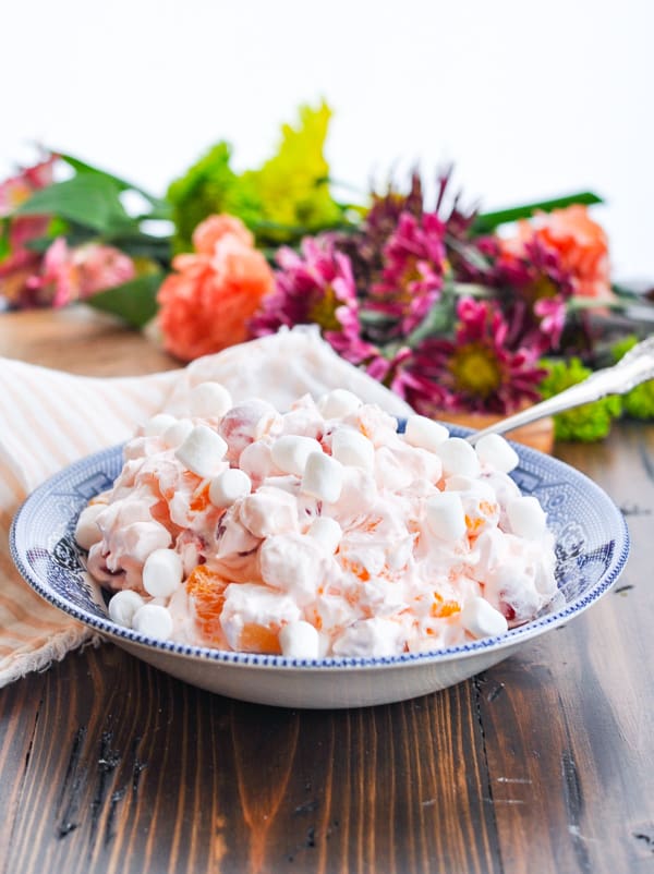Front shot of a bowl of Pink Ambrosia Salad with flowers in the background
