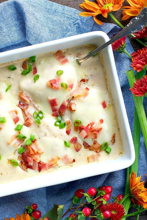 An overhead image of a casserole dish of creamy ranch chicken topped with cheese, bacon bits, and fresh sliced green onions.