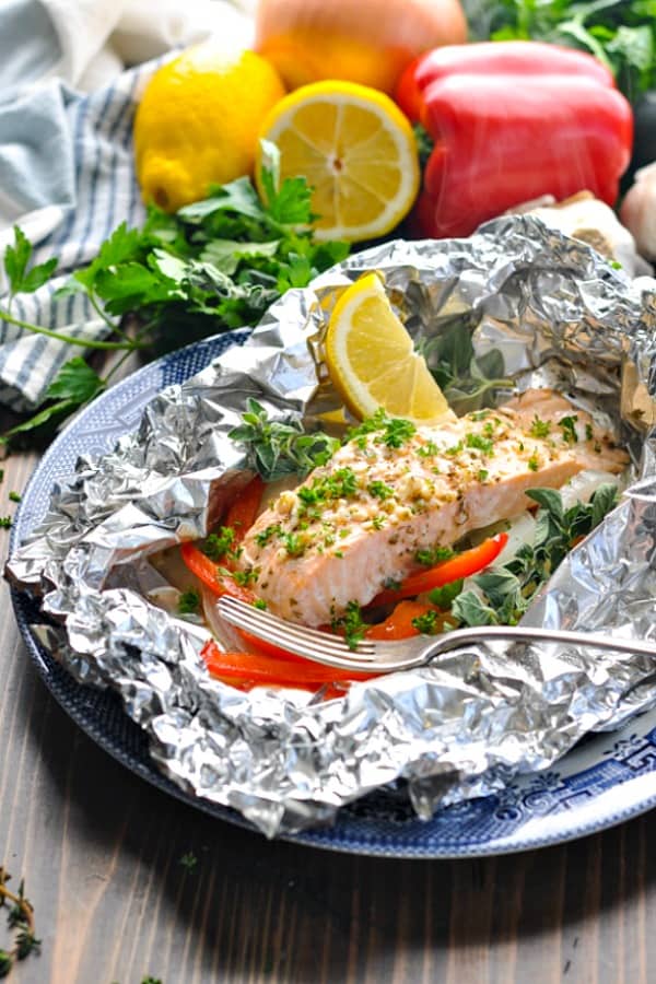 Front shot of baked salmon in a foil packet with zucchini peppers and onions