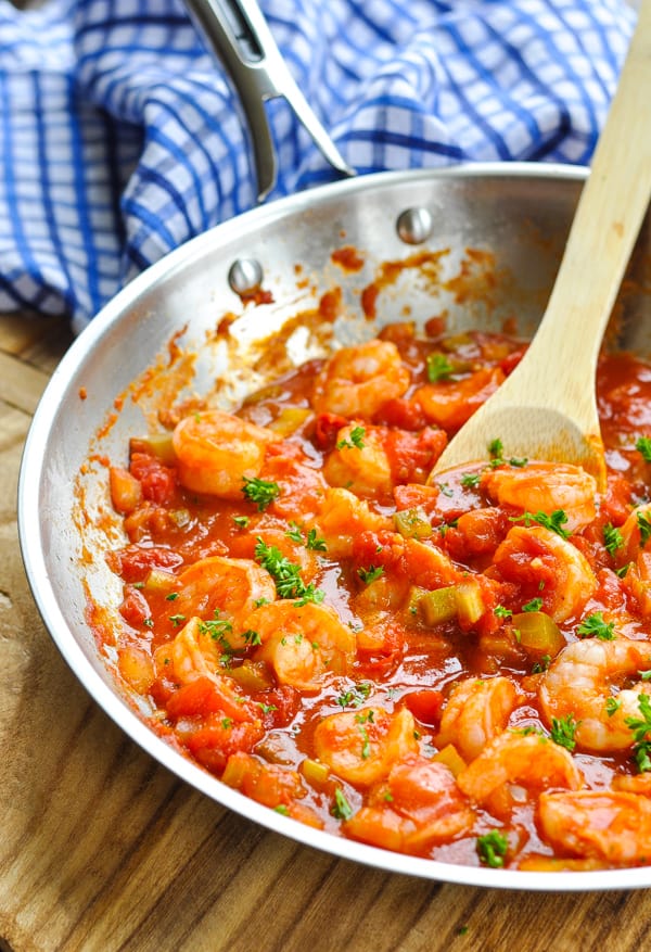 Shrimp Creole in a stainless steel skillet with a wooden spoon and garnished with fresh parsley