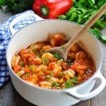 Easy shrimp creole recipe in a white Dutch oven with a wooden serving spoon