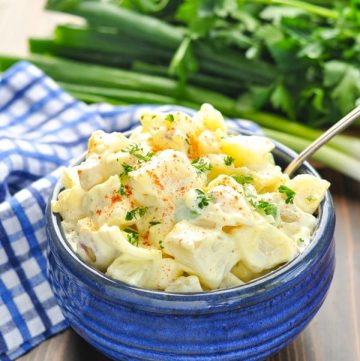 Bowl of potato salad garnished with parsley and paprika