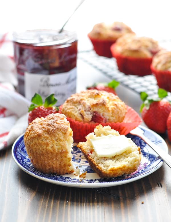 Close up shot of strawberry muffins on a plate with preserves in background