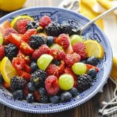 Square side shot of honey lemon fruit salad dressing on a bowl of fresh berries.