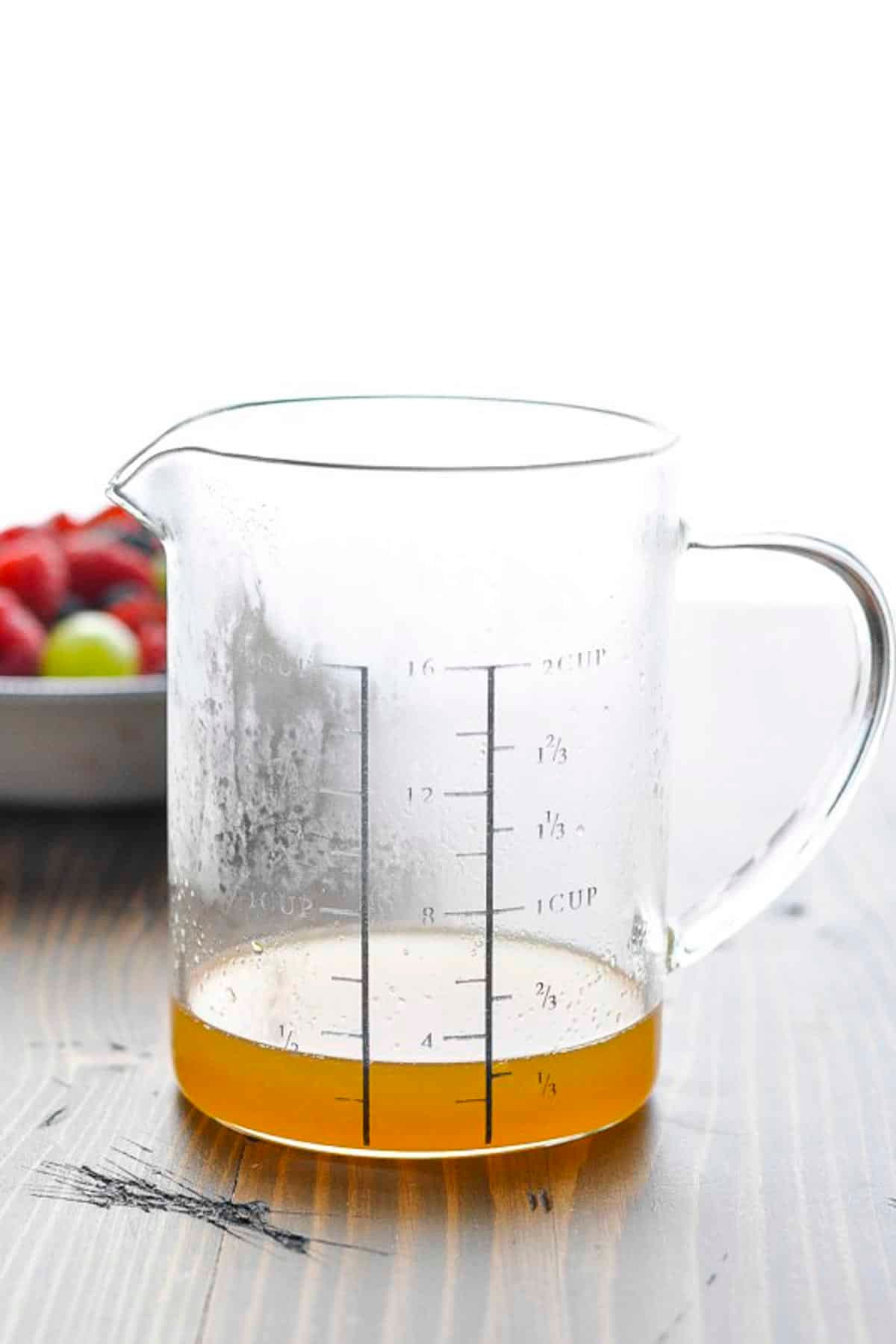 Honey lemon fruit salad dressing in a glass measuring cup.