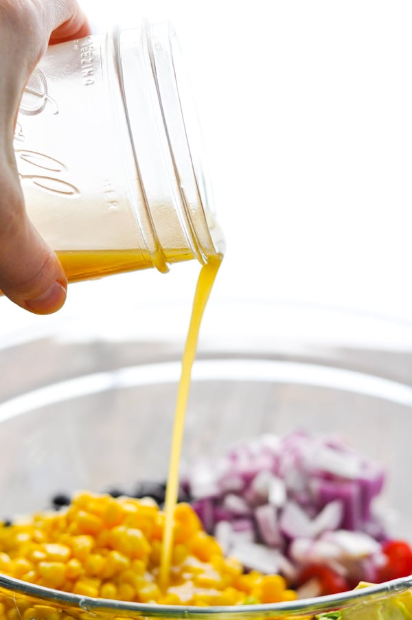 Pouring dressing over corn and black bean salad