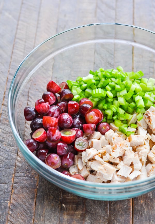 Glass mixing bowl full of diced chicken celery and grapes