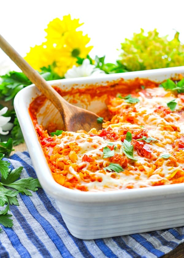 A close up of a stuffed cabbage casserole in a white casserole dish topped with herbs
