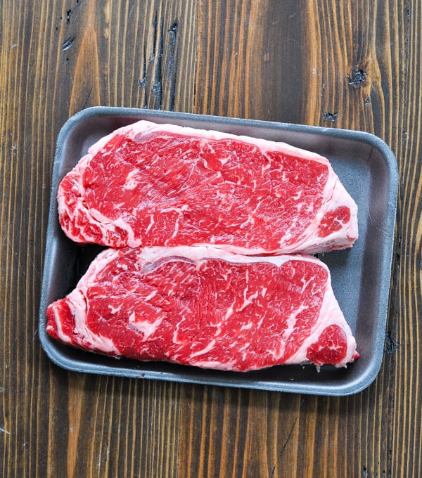 Two raw new york strip steaks in packaging