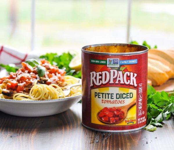 Can of Red Pack Tomatoes in front of a bowl of spaghetti with tomato pesto sauce
