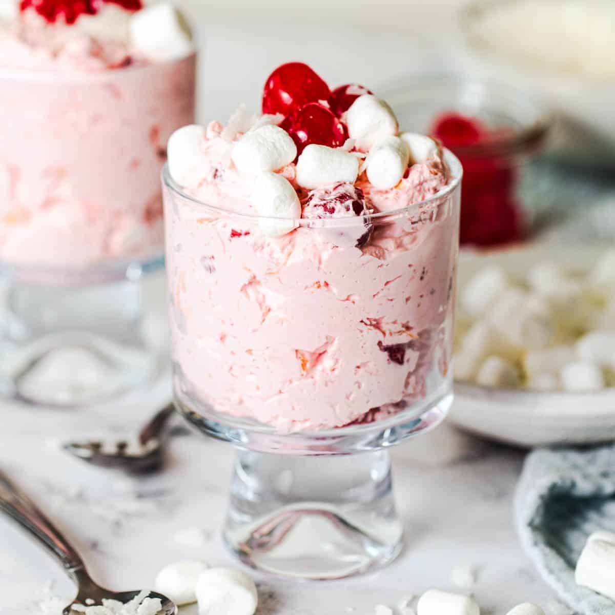 Square side shot of two glass bowls with cherry fluff salad.
