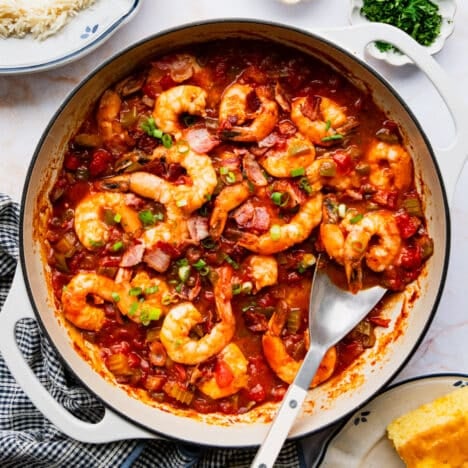 Square overhead shot of shrimp creole in a white cast iron skillet.