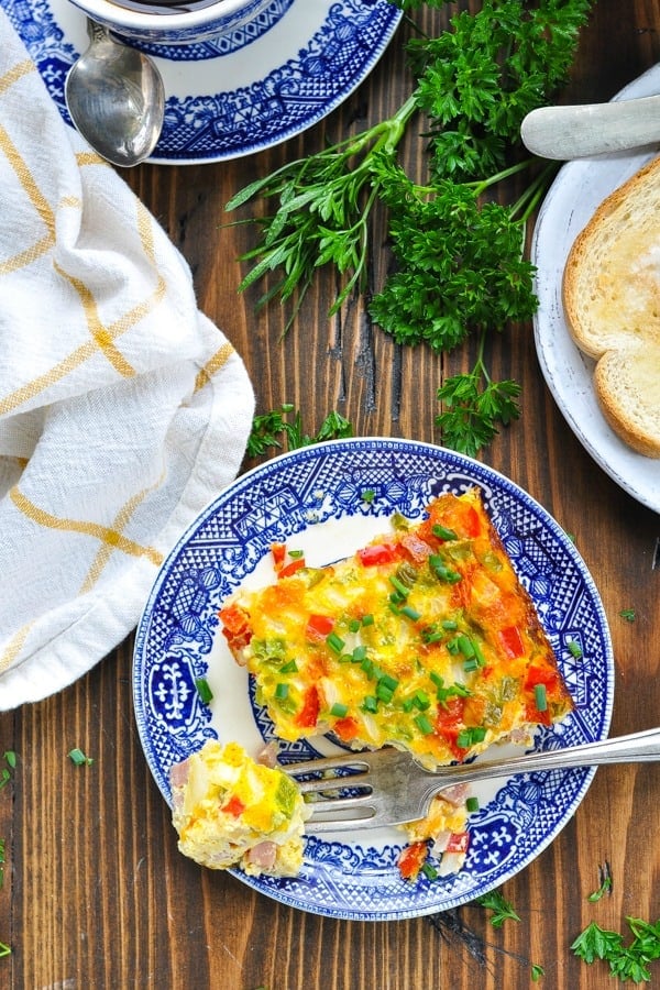 Overhead shot of baked western omelet on a blue and white plate with bite on a fork