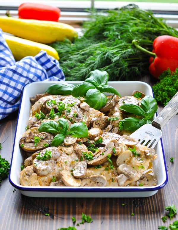 Front shot of a tray of chicken and mushrooms in a white wine sauce
