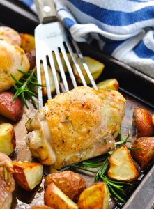 Rosemary chicken on a serving spatula surrounded by potatoes