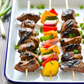 Front shot of easy marinated steak kabobs on a blue and white serving tray