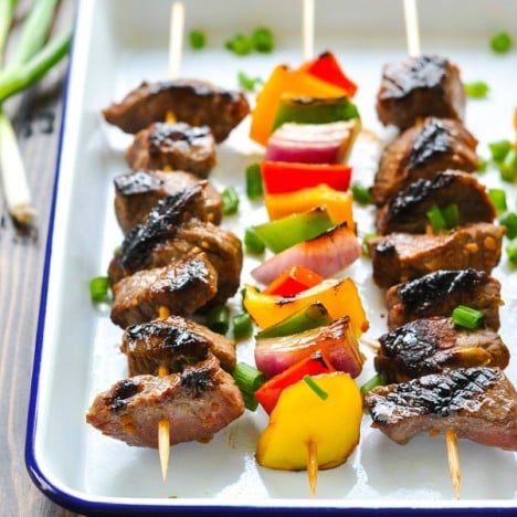 Front shot of easy marinated steak kabobs on a blue and white serving tray