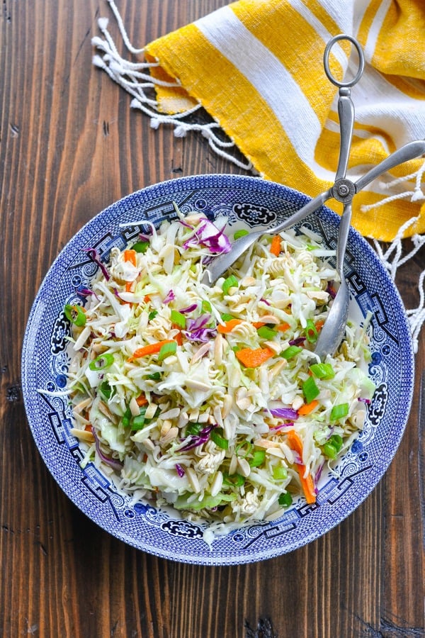 Overhead shot of Ramen Noodle Salad in a blue and white bowl with serving tongs