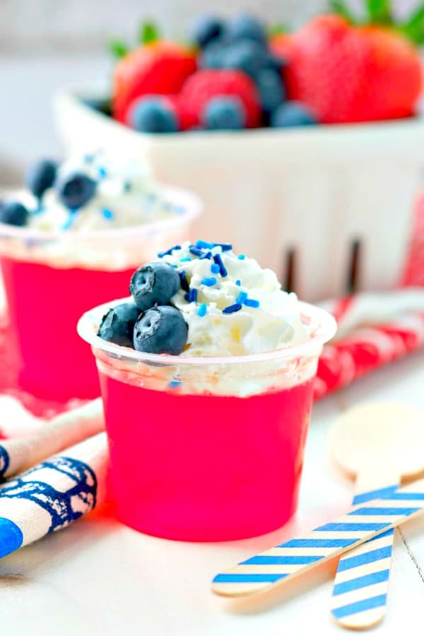 Cup of strawberry Jell-O topped with blueberries and whipped cream