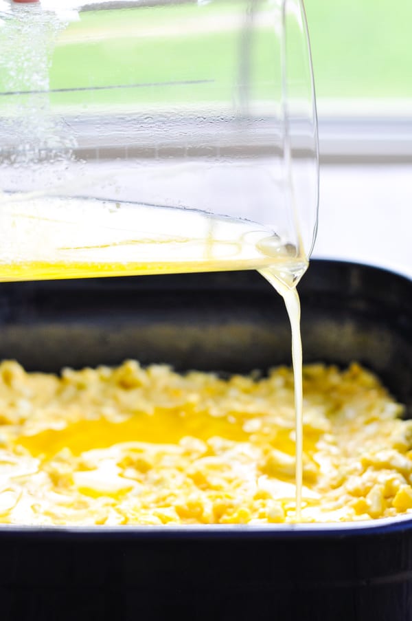 Pouring melted butter over the top of cornbread batter
