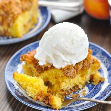 Close up shot of peach cake topped with a scoop of vanilla ice cream