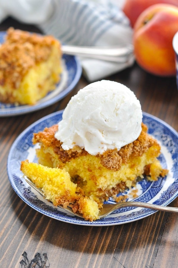 Close up shot of peach cake topped with a scoop of vanilla ice cream