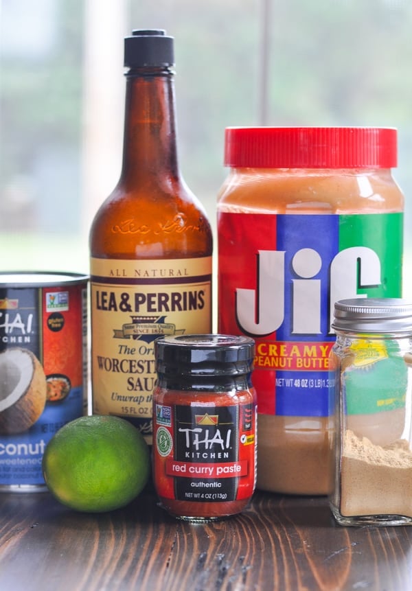 All the ingredients needed to make a homemade curry sauce -- a can of coconut milk, Worcestershire sauce, creamy peanut butter, a lime. red curry paste, and ground ginger.