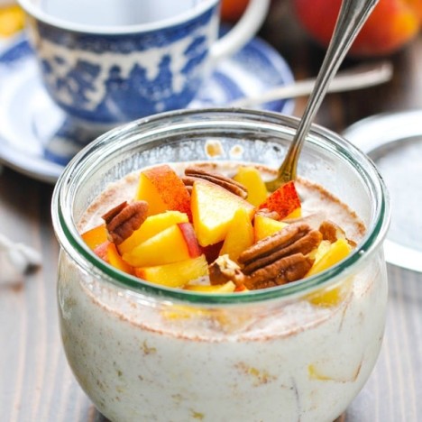 Glass bowl full of overnight refrigerator oatmeal with peaches and pecans
