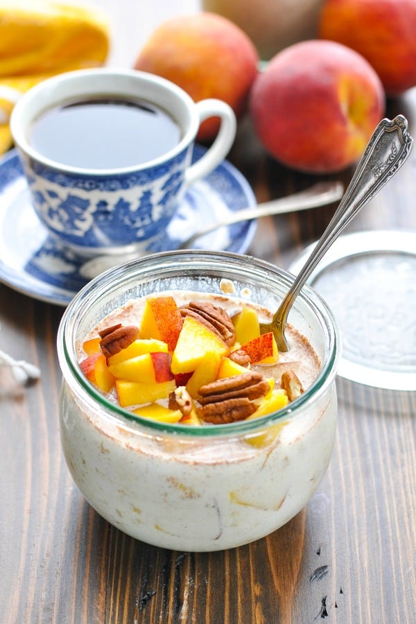 Fresh peaches and pecans on top of bowl of overnight oatmeal