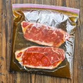 Steaks marinating in a Ziploc bag with the a simple steak marinade for grilling.