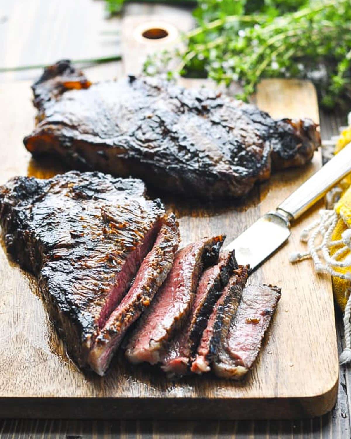 Grilled steaks on a wooden cutting board.