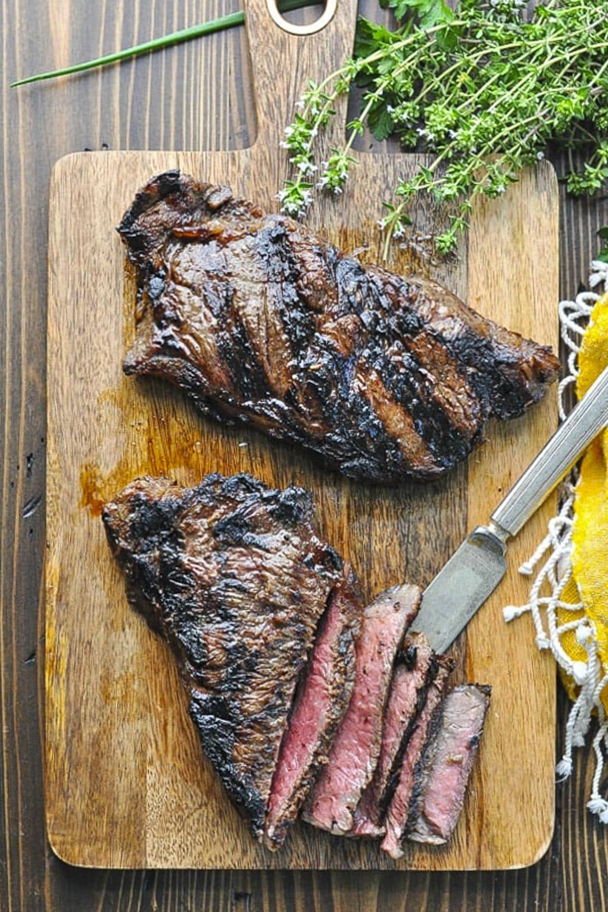 A simple steak marinade for grilling on New York strip steaks on a wooden cutting board.