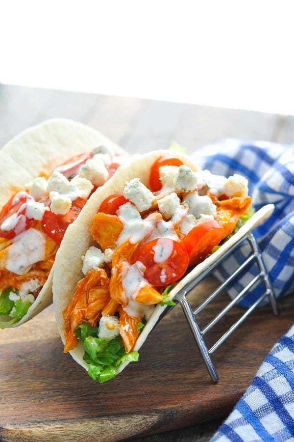 Buffalo chicken with lettuce and tomato in wraps on a wooden surface