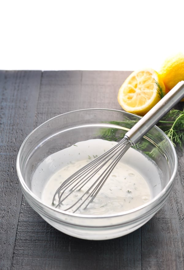 Glass bowl of buttermilk dressing with a whisk