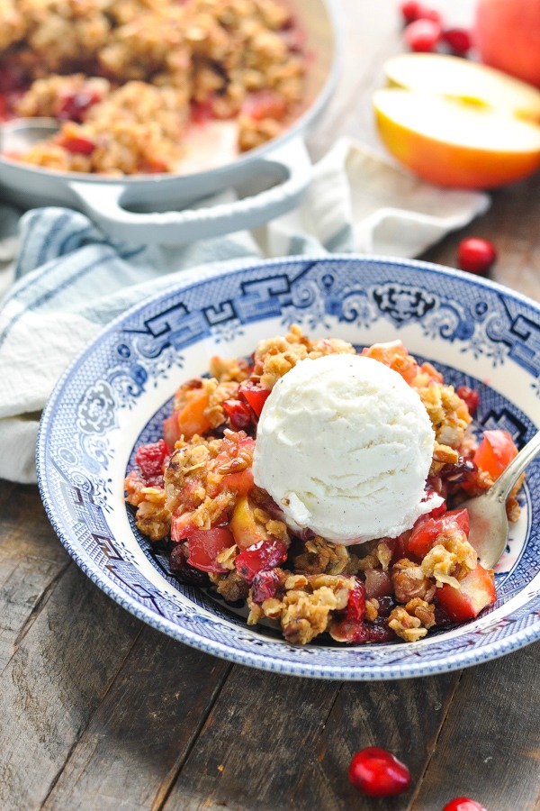 Front shot of cranberry apple crisp in a blue and white bowl with ice cream on top