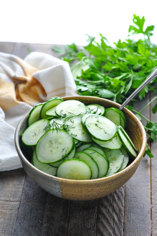 Cucumber salad with dill and vinegar and sugar in a brown clay serving bowl