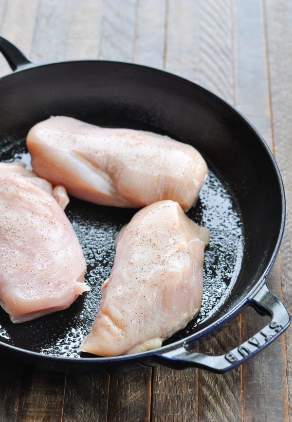 Boneless skinless chicken breasts raw in a cast iron skillet
