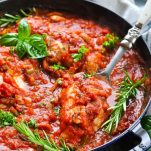 Chicken cacciatore in a cast iron skillet with a serving spoon