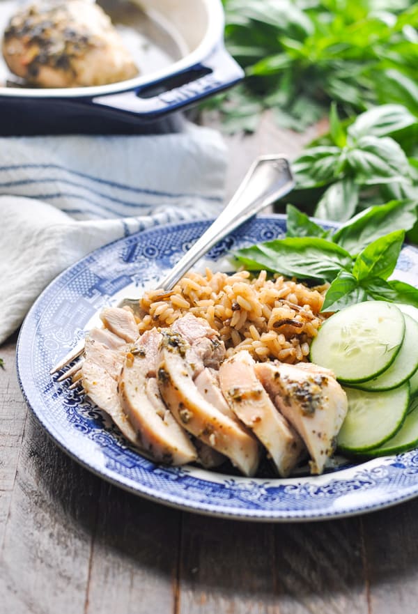 Sliced pesto chicken on a plate with rice and cucumbers