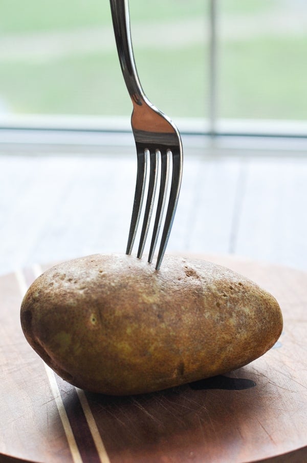 Pricking a russet potato with a fork