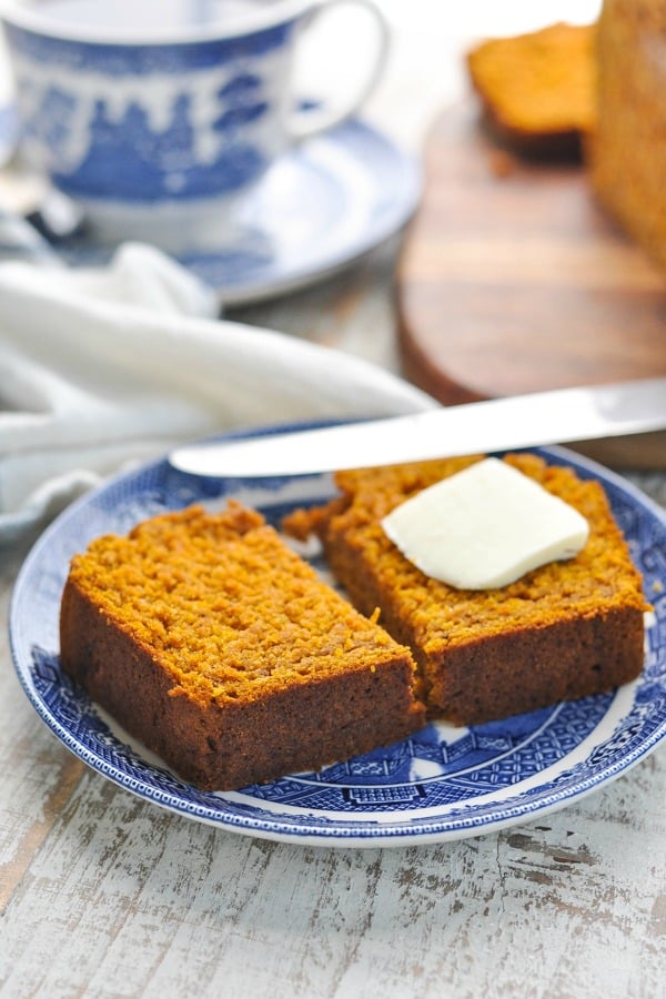 Slice of pumpkin bread recipe on a blue and white plate with a pat of butter on top