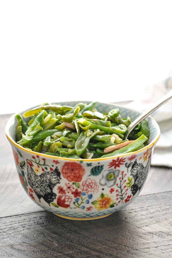 A bowl of slow cooker southern green beans with bacon on a wooden surface