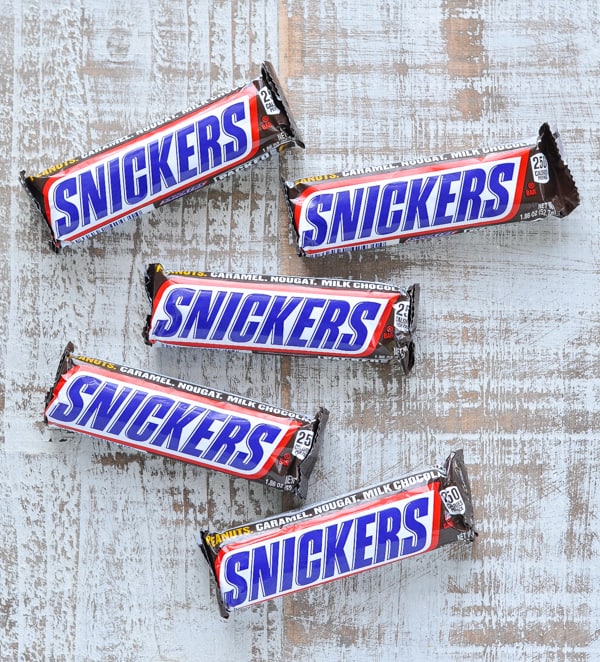Five snickers candy bars on table